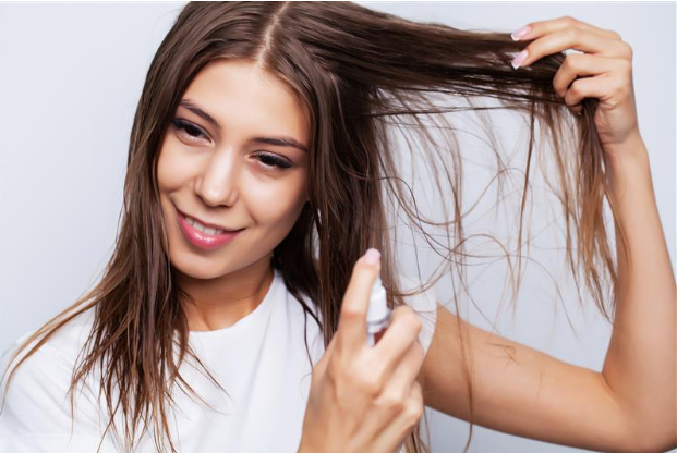 Young woman applies conditioner to restore damaged hair 