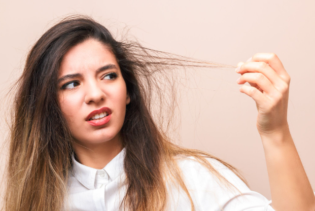 Young woman looking at her rough and damaged hair